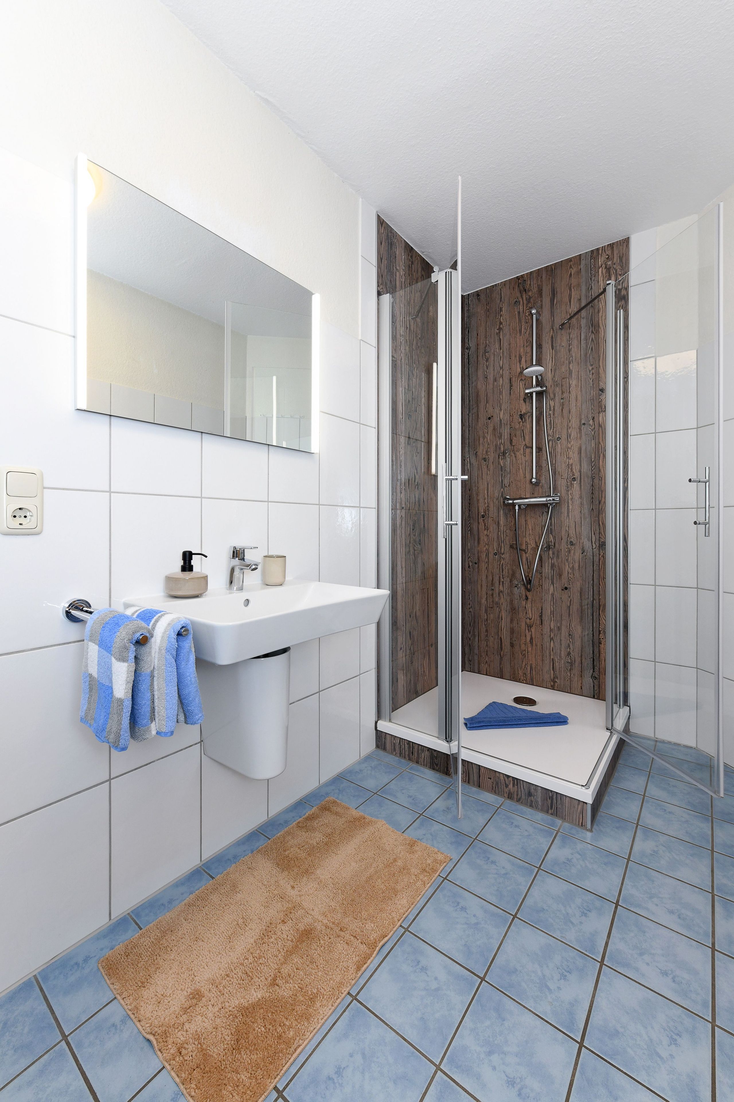 Une salle de bain moderne avec une douche à parois de verre, un lavabo blanc et un miroir au-dessus.