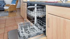 Une cuisine avec des meubles de rangement en bois, un lave-vaisselle, un four à micro-ondes et un évier.