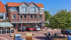 Un bâtiment à deux étages, doté d’un toit recouvert de tuiles rouges, d’un balcon et d’une devanture de magasin avec une enseigne.