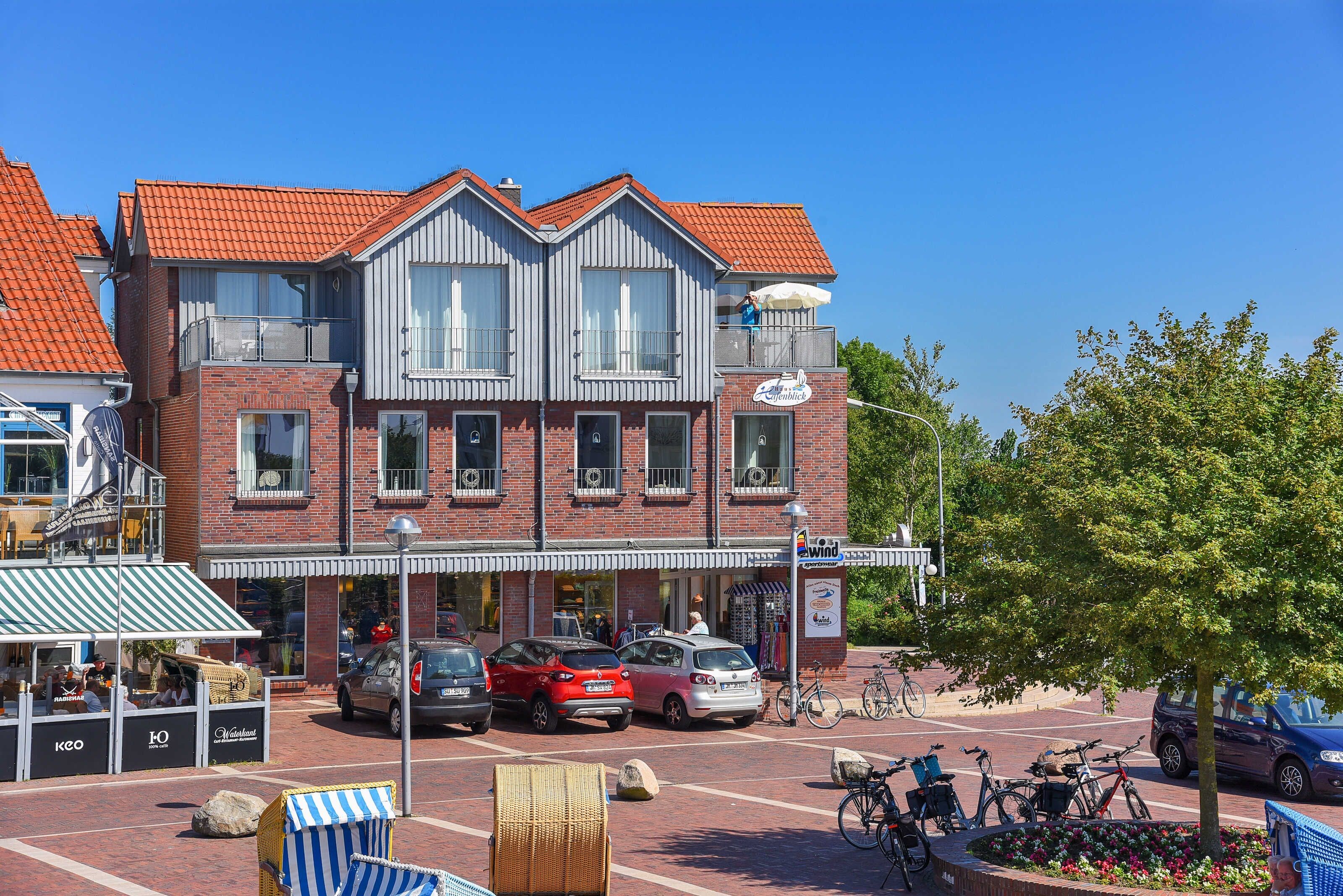A two-story building with a red-tiled roof, a balcony, and a storefront with a sign.