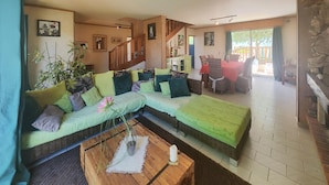 A spacious living area with a large sectional sofa, a wooden coffee table, and a dining area with wicker chairs. - Awesome home in Tourbes (Tourbes)