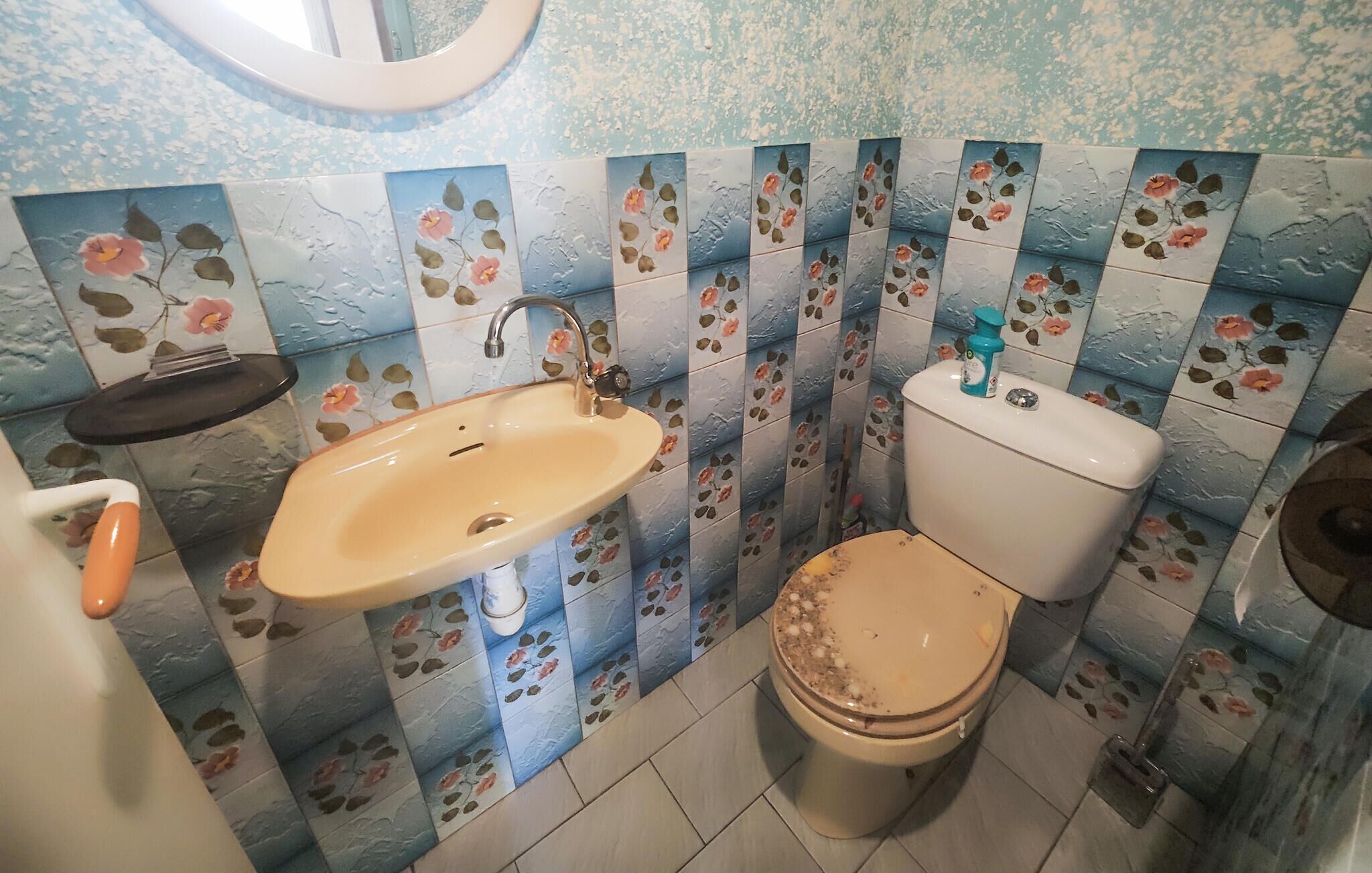 Un baño con lavamanos, inodoro y un pequeño estante.