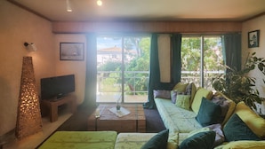 A living room with a sofa, a television, and a large window with curtains. - Awesome home in Tourbes (Tourbes)