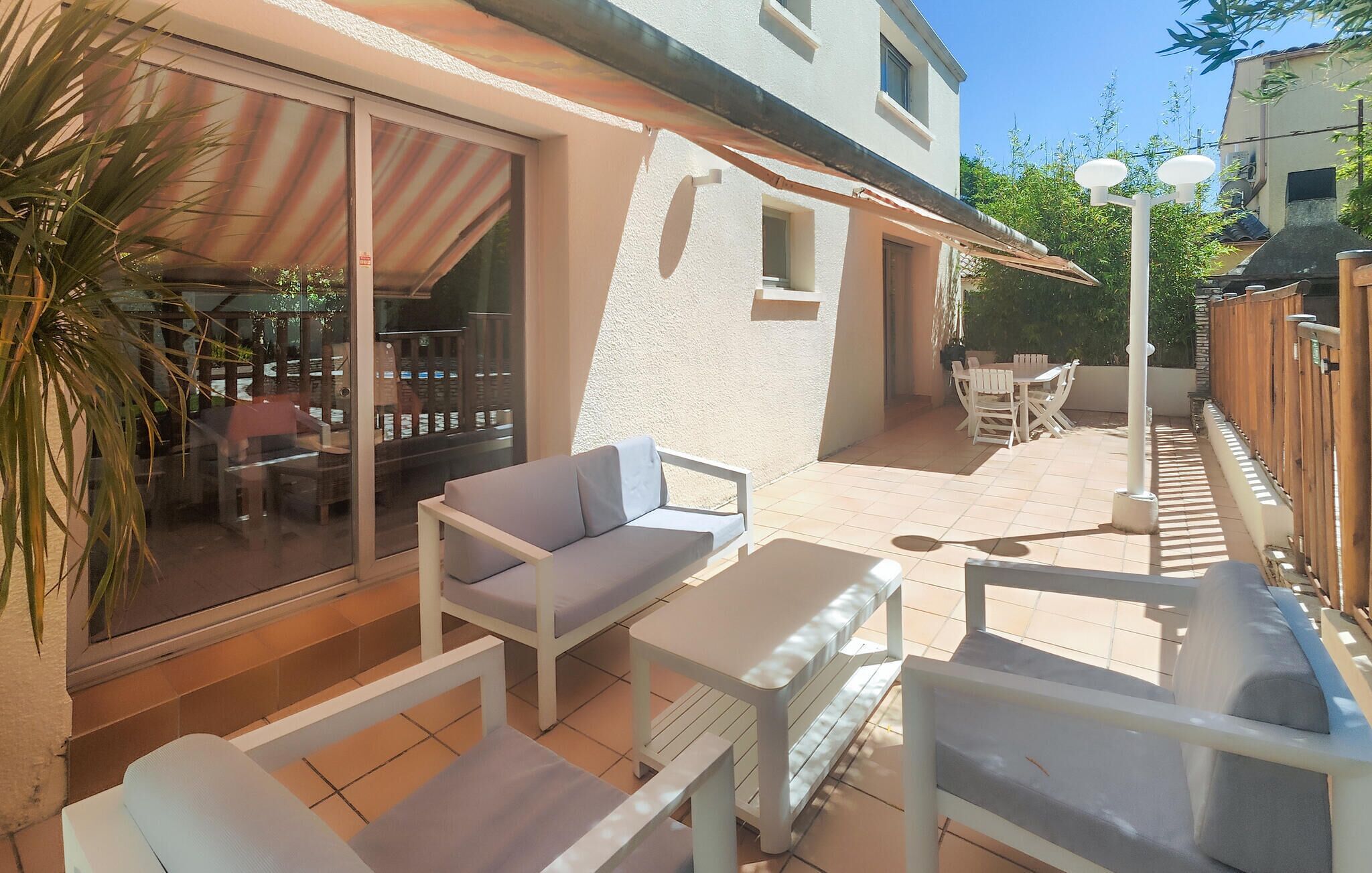 A patio with white furniture, a glass door leading to a room, and a small table.