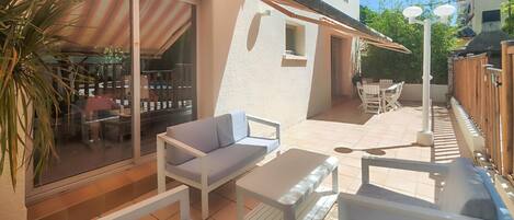 A patio with white furniture, a glass door leading to a room, and a small table.
