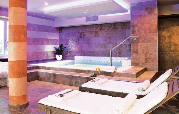 Ein Wellnessbereich mit Whirlpool, zwei Liegesesseln und einer Topfpflanze.