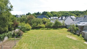 A residential area with a well-maintained lawn, houses with pitched roofs, and a dense tree line in the background. - Pet friendly home in Tredrez-Locquemeau (Tredrez-Locquemeau)