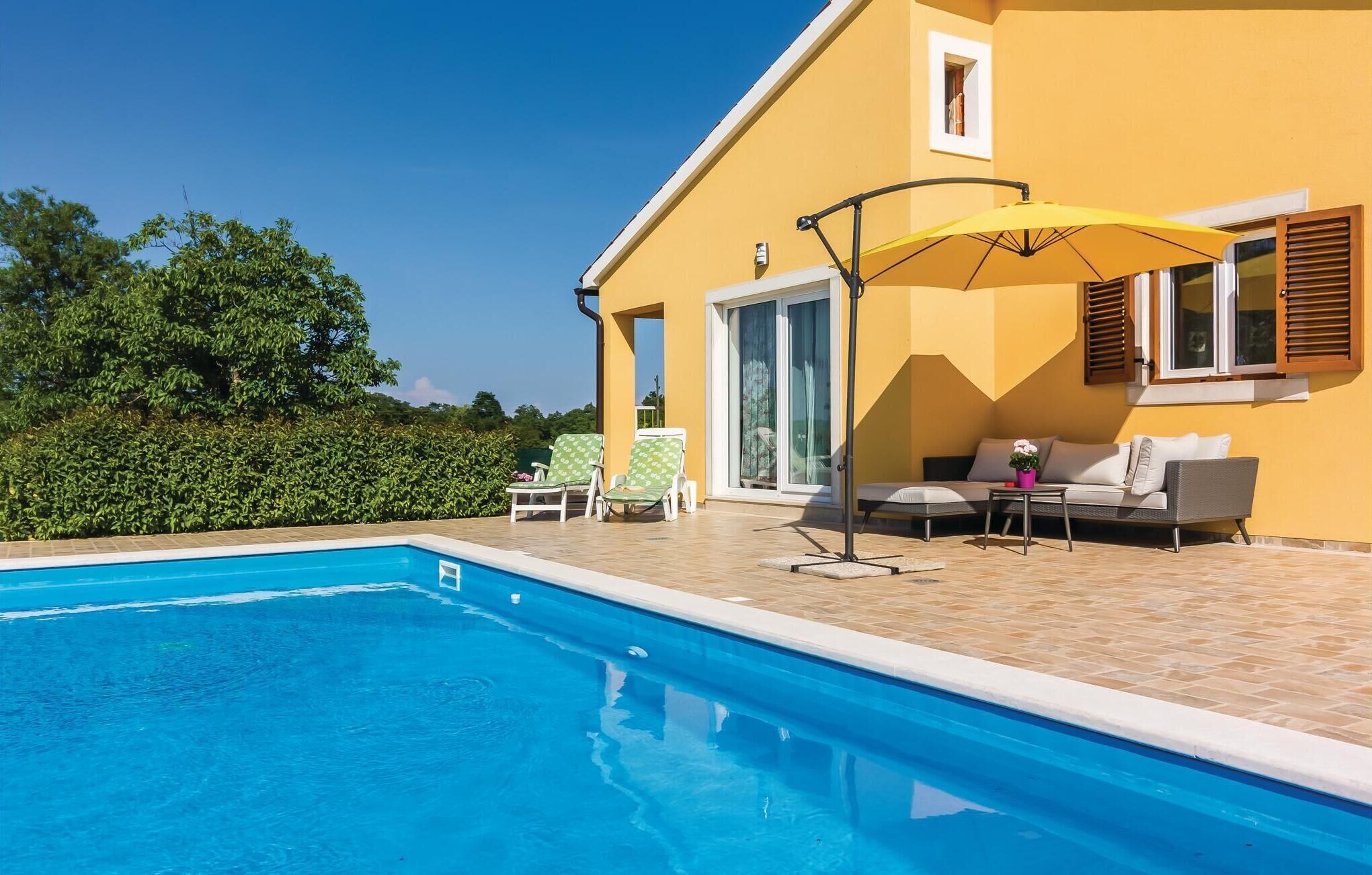 Ein Schwimmbad mit einem gelben Haus im Hintergrund.