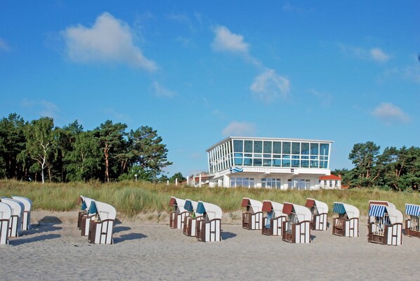 A beachside building with a modern design, rows of beach chairs, and a clear view of the ocean.