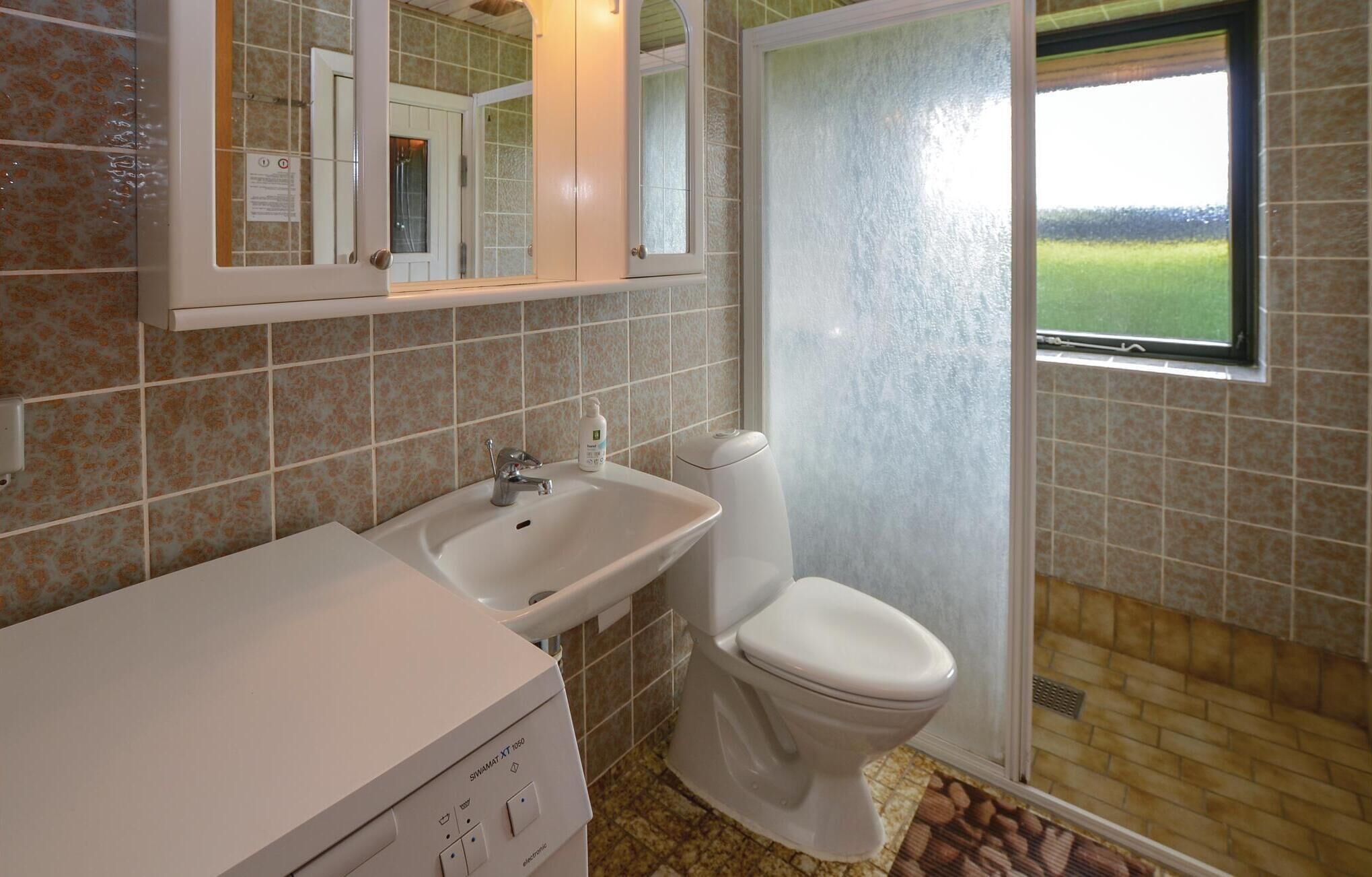 A bathroom with a white sink, toilet, and shower area.