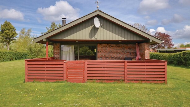 A small, single-story building with a sloped roof, a brick exterior, and a red wooden fence surrounding the area. - Cozy home in Sydals with sauna (Sydals)
