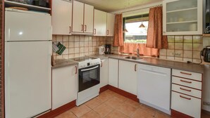 A compact kitchen with white cabinets, a stove, oven, and dishwasher. - Cozy home in Sydals with sauna (Sydals)