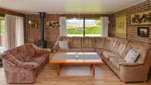 A cozy living room with a brick wall, a large sofa, a smaller sofa, and a wooden coffee table. - Cozy home in Sydals with sauna (Sydals)