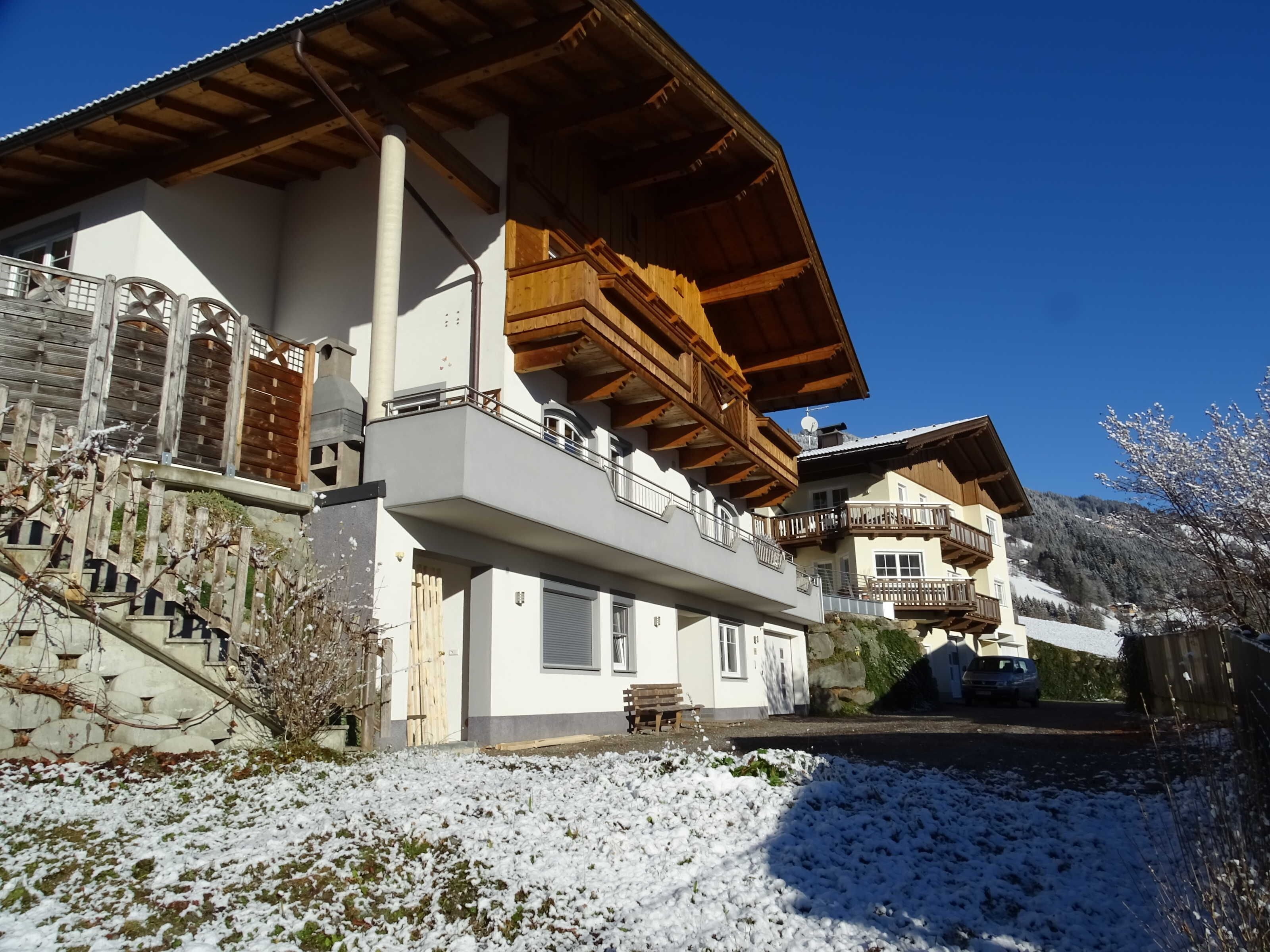 A multi-story building with balconies, a wooden facade, and a snow-covered ground.