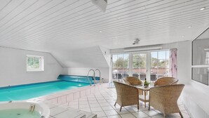 Piscina com hidromassagem, mesa com cadeiras e vista para o exterior.