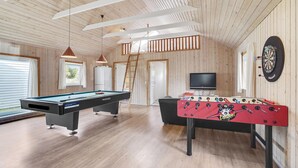 Um quarto amplo com mesa de bilhar, mesa de futebol e televisão.