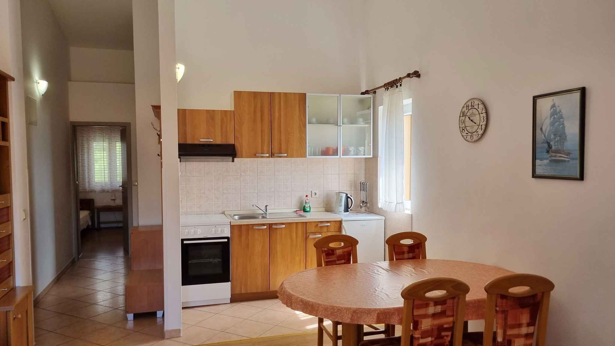 Une cuisine de taille réduite, dotée de meubles de rangement en bois, d’une cuisinière et d’une table à manger avec des chaises.