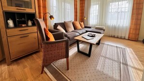 Un salon comprenant un canapé, des fauteuils, une table basse, un meuble et une lampe.
