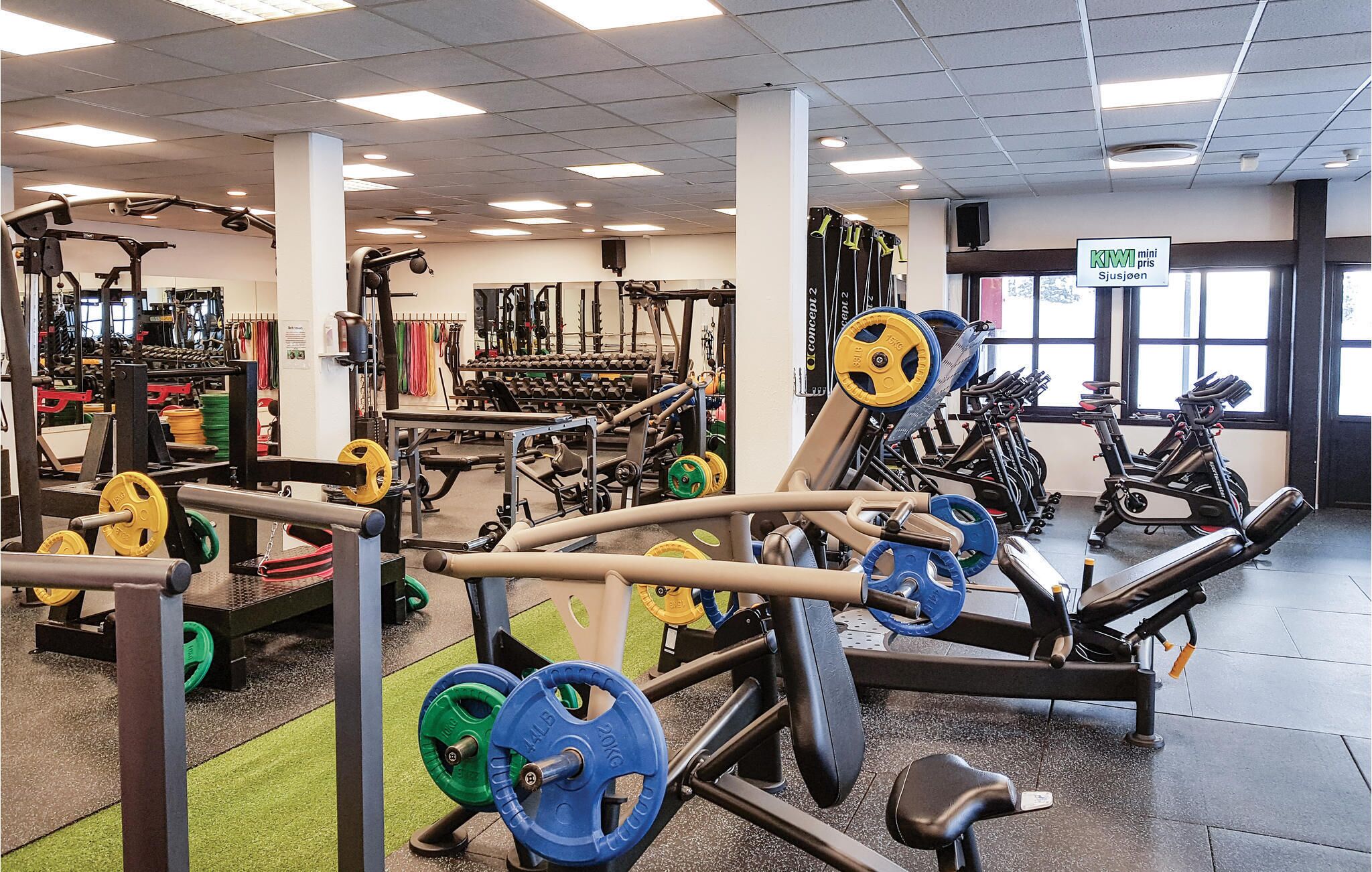 A gym with various exercise equipment, including weight machines, free weights, and cardio machines.