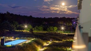 Une vue nocturne d’un hôtel avec une piscine, entouré d’arbres et éclairé par des lampadaires.
