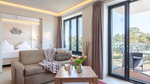 A modern hotel room with a sofa, a coffee table, and a view of the outdoors. - Cozy apartment in Binz with WiFi (Prora/Rügen)