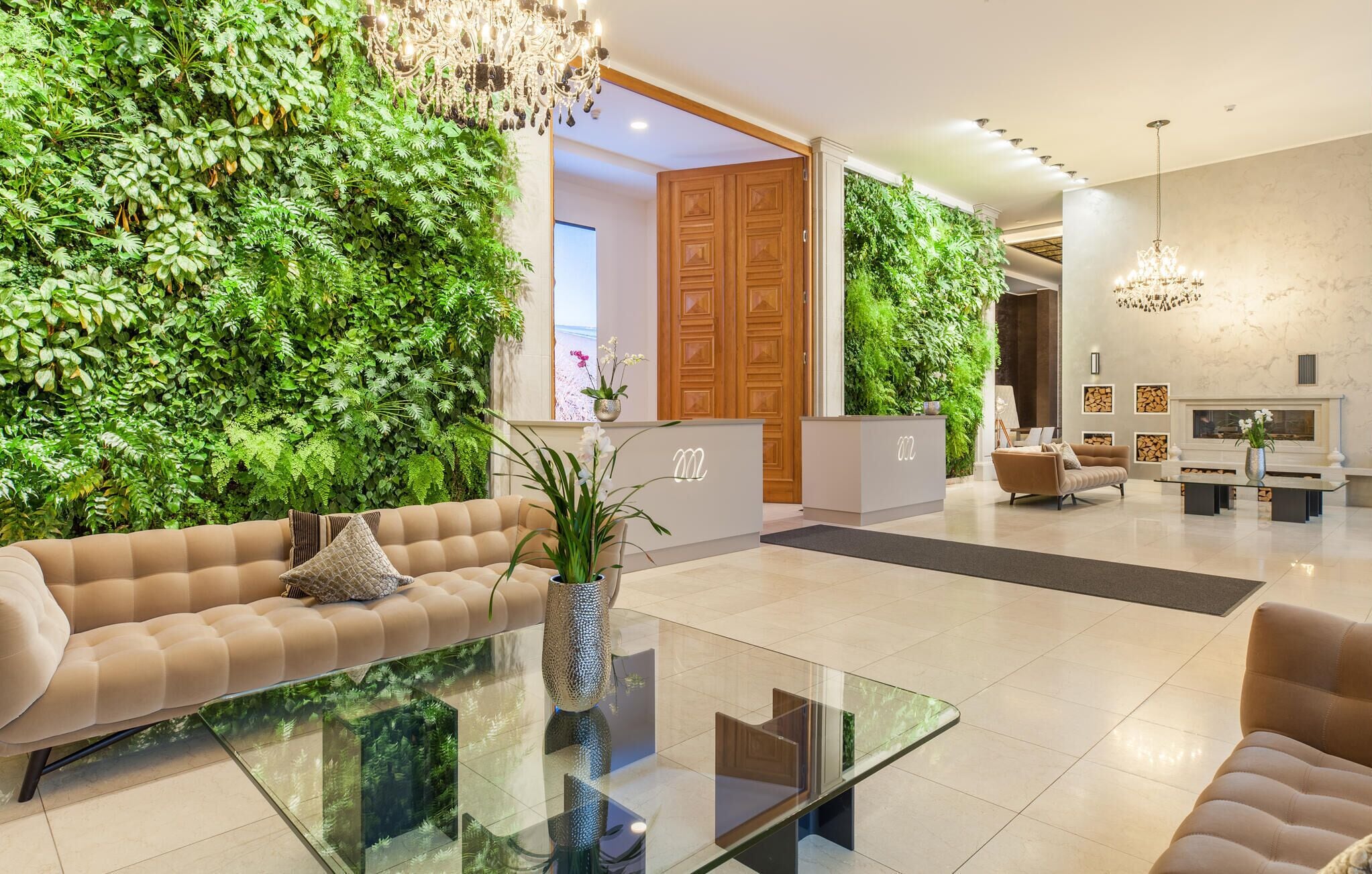 Un hall d’hôtel moderne avec un canapé, une table basse en verre, un comptoir d’accueil et des murs verts.