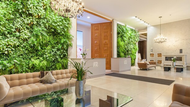 A modern hotel lobby with a sofa, a glass coffee table, a reception desk, and green walls. - Cozy apartment in Binz with WiFi (Prora/Rügen)