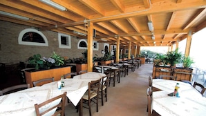 Un espace de restauration intérieur avec des tables et des chaises en bois, des plantes en pot et des murs en briques.