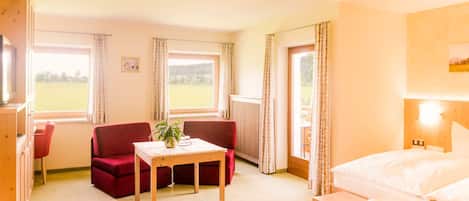 Ein Hotelzimmer mit einem Bett, einem roten Sofa, einem Holztisch und einem Fenster mit Vorhängen.