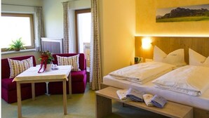 Quarto de hotel com uma cama, um sofá, uma mesa e uma janela com cortinas.