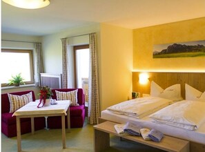 Ett hotellrum med en säng, en soffa, ett bord och ett fönster med gardiner.