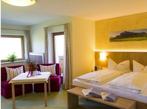 Ein Hotelzimmer mit Bett, einer Couch, einem Tisch und einem Fenster mit Vorhängen.