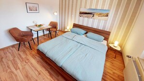 Una habitación de hotel con una cama grande, un escritorio, dos sillas y una mesita.