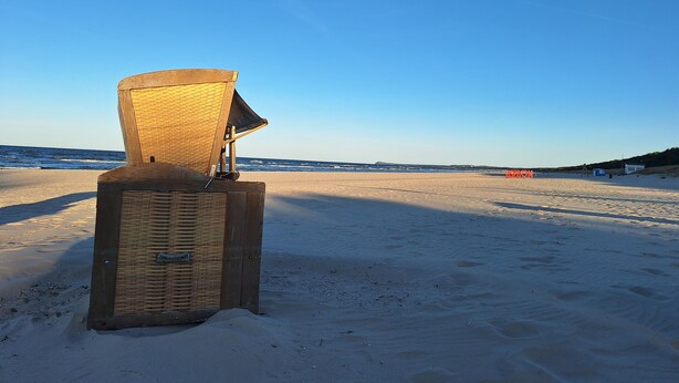 Una playa con una estructura de madera, posiblemente una cabaña, y cielo despejado.