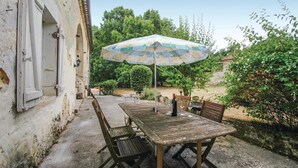 An outdoor patio with a wooden table and chairs, an umbrella, and a stone wall.