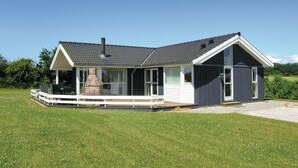 Ein zweistöckiges Haus mit Kamin aus Stein, einer Veranda und einem großen Fenster.