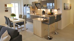 Eine moderne Küche mit einer zentralen Kochinsel, Barhocker und einem Essbereich mit Tisch und Stühlen.