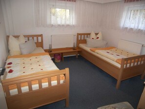Una habitación con dos camas de madera, un banco y un radiador.
