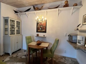 A dining area with a table, chairs, a chandelier, a cabinet, and a microwave on a countertop. - Midsummer Night's Dream - Kunsthof Salsitz (Lohme auf Rügen)