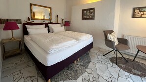 A hotel room with a large bed, two bedside lamps, a chair, a small table, a mirror, and a picture on the wall. - Midsummer Night's Dream - Kunsthof Salsitz (Lohme auf Rügen)