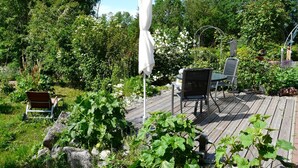 A wooden deck with a white umbrella, a metal chair, and a table. - Midsummer Night's Dream - Kunsthof Salsitz (Lohme auf Rügen)