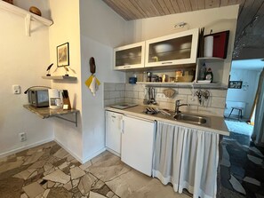 Een kleine keuken met een vaatwasser, een koffiezetapparaat en een spoelbak.
