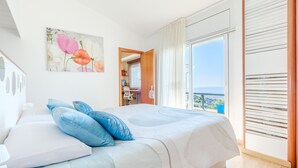 Een slaapkamer met een bed, een schilderij, uitzicht en een balkon.