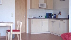 A compact kitchen with white cabinets, a microwave, and basic appliances. - Apartment Elly - House Uhleck (Lohme)