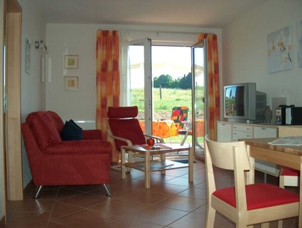 Ein Wohnzimmer mit einem roten Sofa, einem Holzesstisch und einem Fernseher.