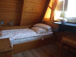 Una habitación de cabaña de madera con una cama, un escritorio y una lámpara.