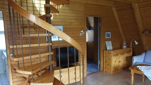 Ein Holzinnenraum mit einer Wendeltreppe, einem Fernseher und einem Essbereich.