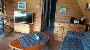 Ein Holzinnenraum mit Fernseher, Holzschränken, einer Couch und einer gemusterten Tischdecke.