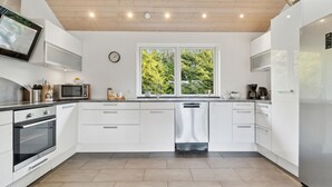A modern kitchen with white cabinetry, stainless steel appliances, a large window, and a view of greenery outside. - Gorgeous home in Vejby with sauna (Vejby)