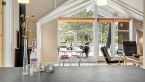 A modern interior with a dining area, a fireplace, and large windows offering a view of the outdoors. - Beautiful home in Nexø with WiFi (Nexø)
